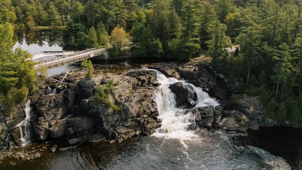 Aerial view of a stunning waterfalls surrounded by lush forest in Bracebridge.