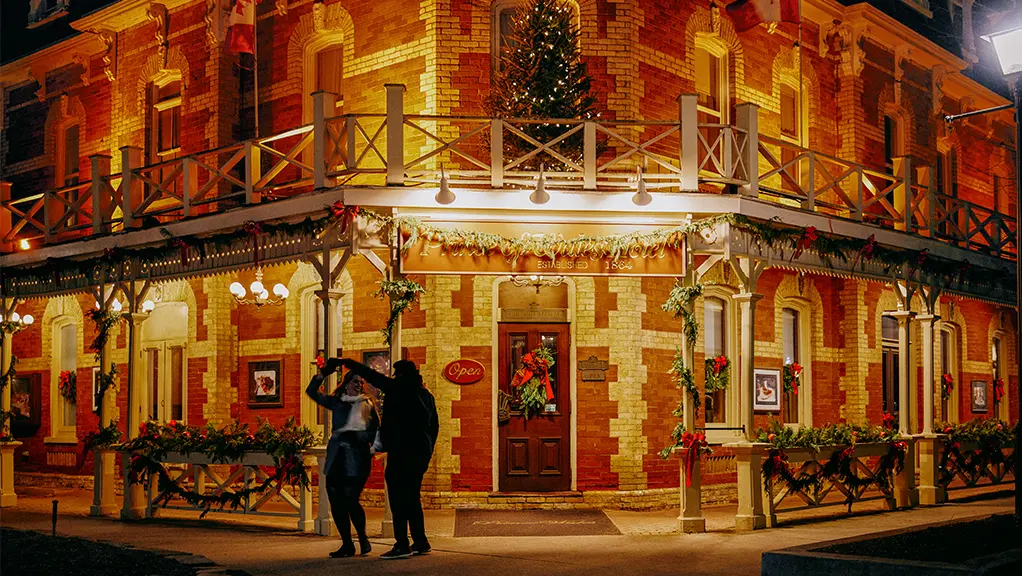 Historic corner building illuminated with warm lights and festive decorations at night.