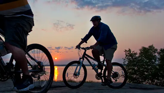 Deux cyclistes admirent le suset sur le lac.