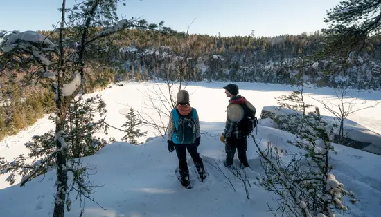 Luftaufnahme von drei Personen, die mit Schneeschuhen einen Pfad entlangwandern.