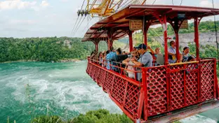 A group of people travelling across the falls in an aero car.