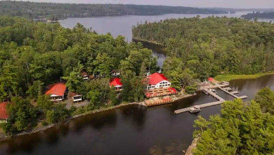 Vista aérea de un remoto albergue de pesca en el norte de Ontario, accesible solo por barco y rodeado de agua y bosque.