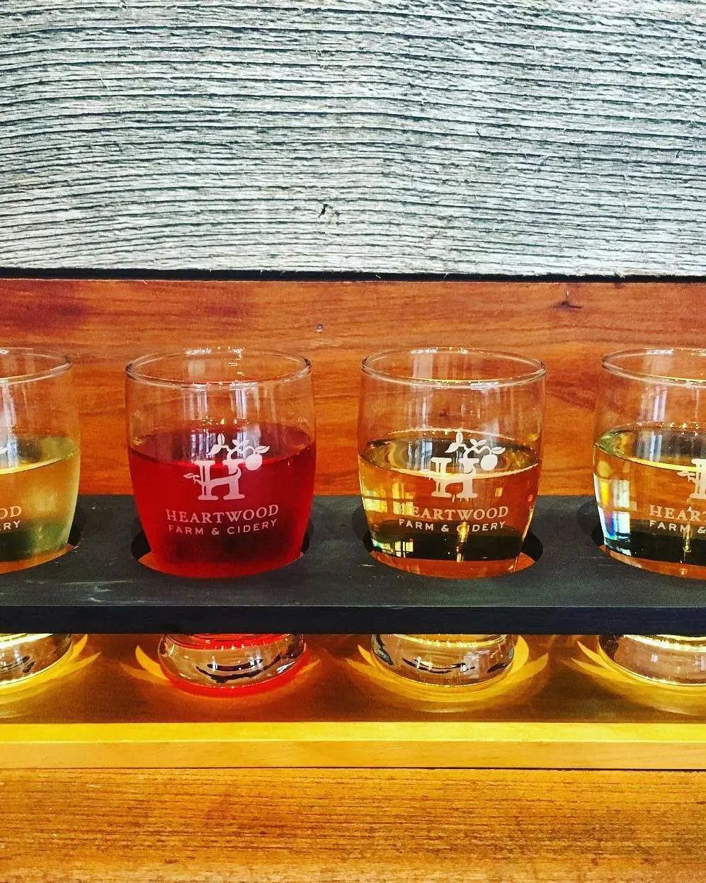 A flight of 4 ciders sitting on a wood table