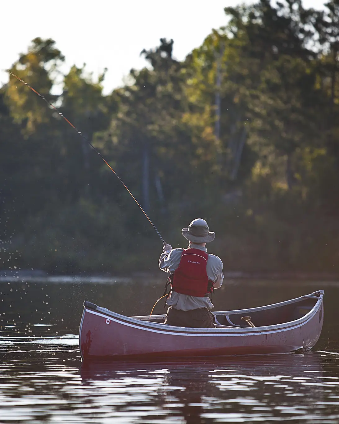 A man casting his line from a boat on a lake