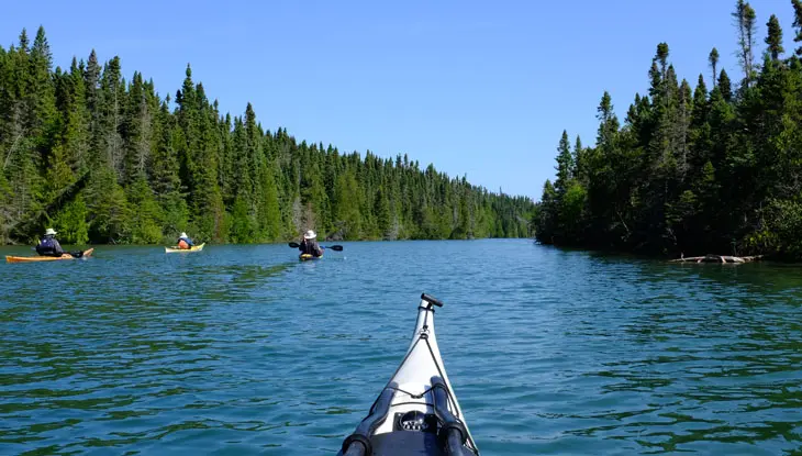 Ein Kajak zeigt auf einen breiten Fluss, der von Wald umgeben ist.