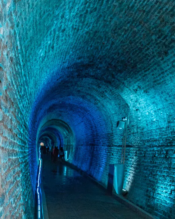 Blue light illuminates a stone tunnel.