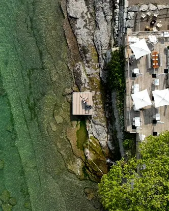 岩の多い海岸と水色のオンタリオ湖に面したレイクサイド モーテルの明るいデッキの航空写真。