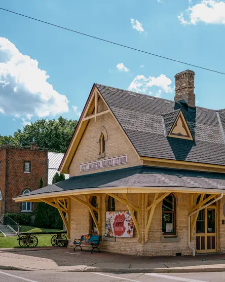 El Centro de Artes de Station en Tillsonburg, ubicado en una estación de tren histórica restaurada, fotografiado en un soleado día de verano con nubes dispersas.