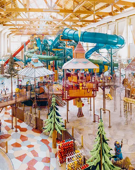 Ein farbenfroher Indoor-Wasserpark mit Planschzone, Poolbereich und Wasserrutschen.