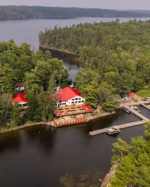 Vista aérea de un remoto albergue de pesca en el norte de Ontario, accesible solo por barco y rodeado de agua y bosque.