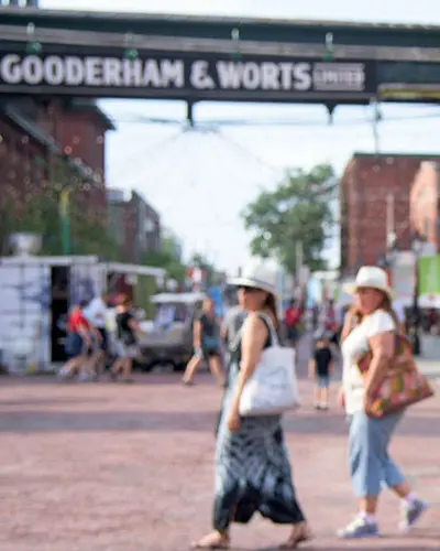 2 人の女性が石畳の道を横切る中、女性の後頭部が石畳の道に面しているところ。