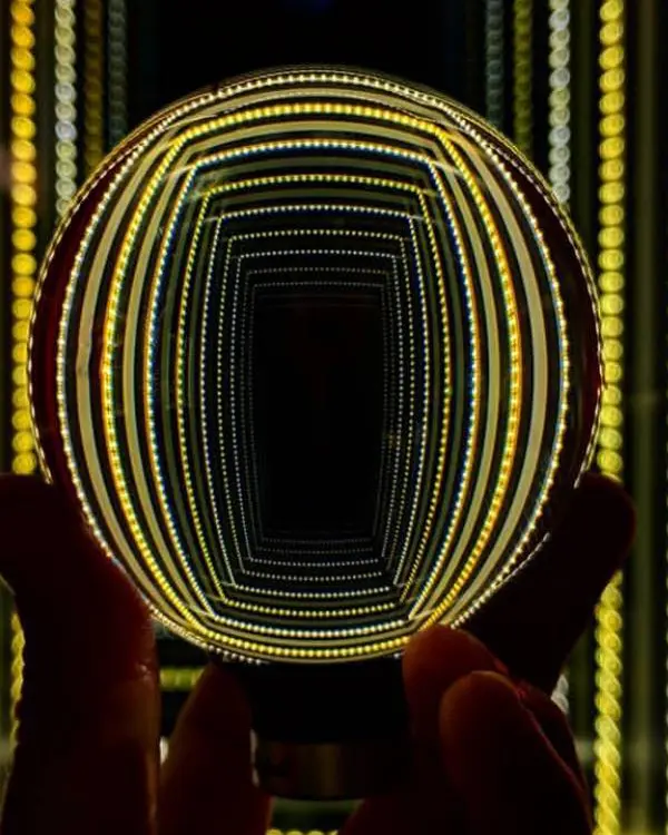 Die Hand einer Person hält einen Globus hoch, der Lichter reflektiert.