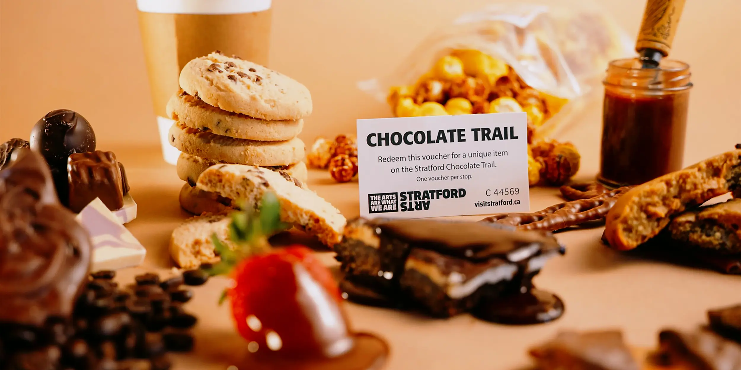 Surtido de dulces y postres de chocolate artesanal dispuestos sobre una mesa junto con granos de café y cacao.